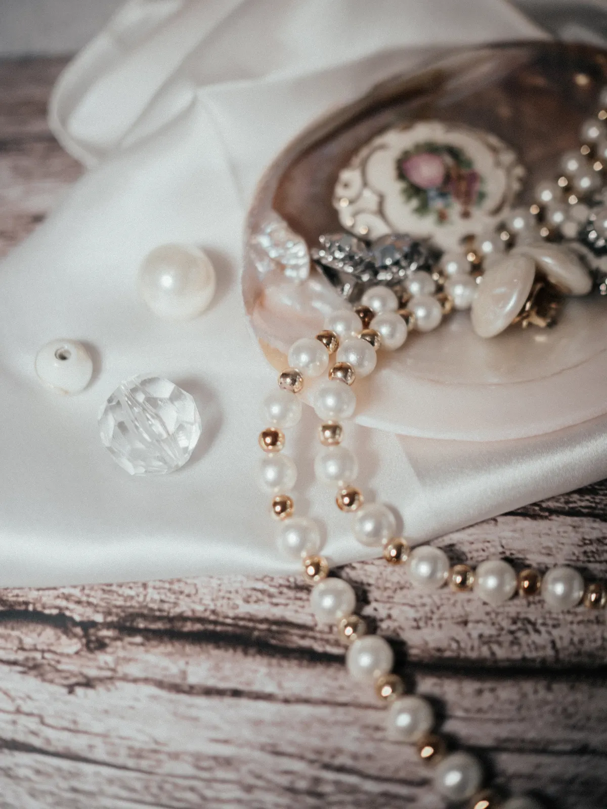 Pearl-style beads and decorative jewelry arranged on pale fabric