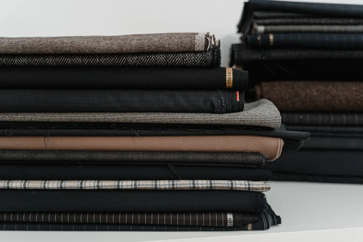 Folded tailoring fabrics in charcoal, taupe and brown, with herringbone, checks and pinstripes