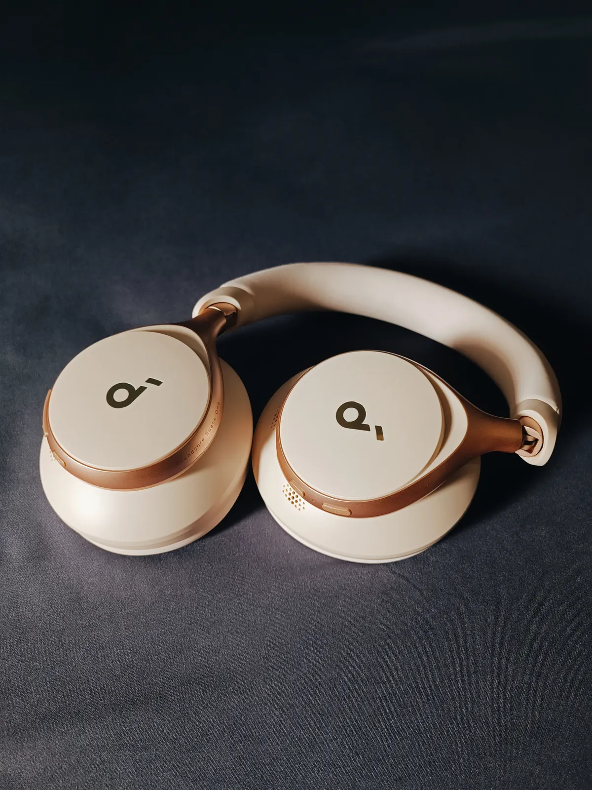 Beige over-ear headphones resting on a dark surface